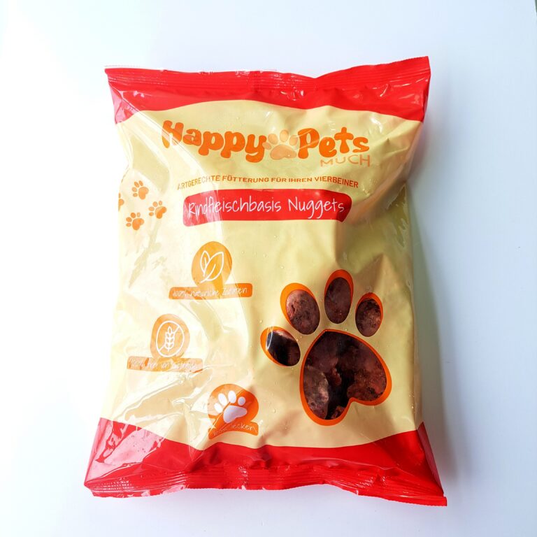 eine bunte Tüte mit der Aufschrift HappyPets man sieht eine durchsichtige Pfote darunter kann man Fleisch Bröckchen erkennen