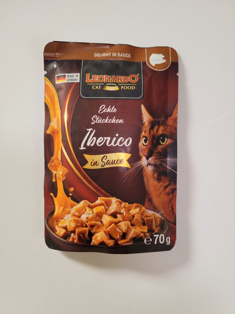 Zu sehen ist eine Tüte mit einem Kätzchen drauf. Davor steht ein Teller mit kleinen Fleischstückchen appetitlich angerichtet